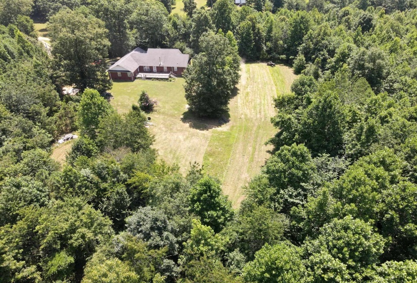 Aerial perspective of a brick residence featuring a partially covered rear deck