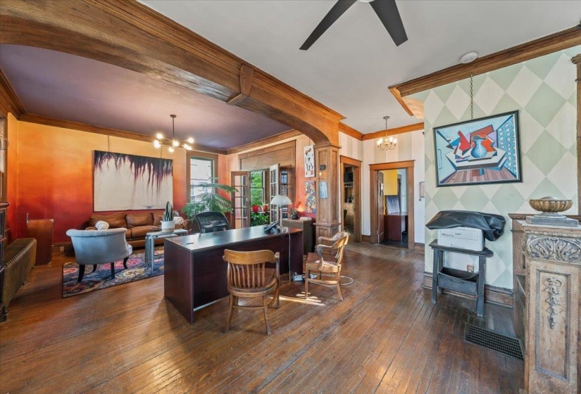 Home office with hanging lights, dark wood-type flooring, crown molding, and arched walkways