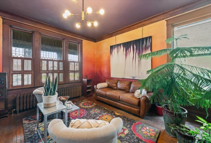 Living area with radiator heating unit, healthy amount of natural light, hardwood / wood-style floors, and crown molding