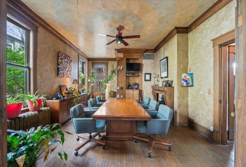 Dining area with dark wood-style floors, ornamental molding, ceiling fan, and a glass covered fireplace