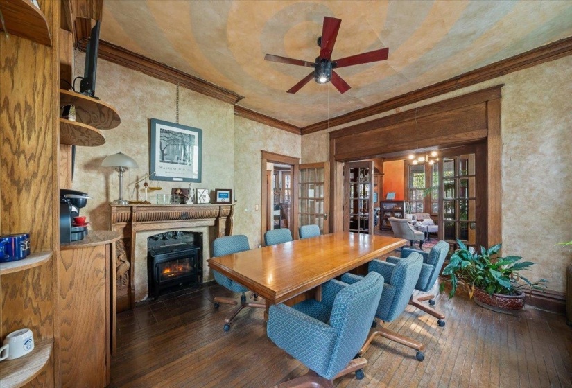 Dining area featuring hardwood / wood-style floors, ornamental molding, a fireplace with flush hearth, and a ceiling fan