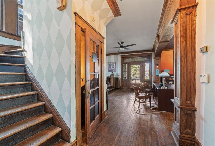 Entrance foyer with dark wood-style flooring, ceiling fan, ornamental molding, and radiator
