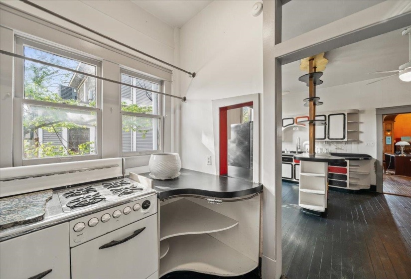 Kitchen with gas range gas stove, backsplash, dark wood-style flooring, dark countertops, and stainless steel fridge