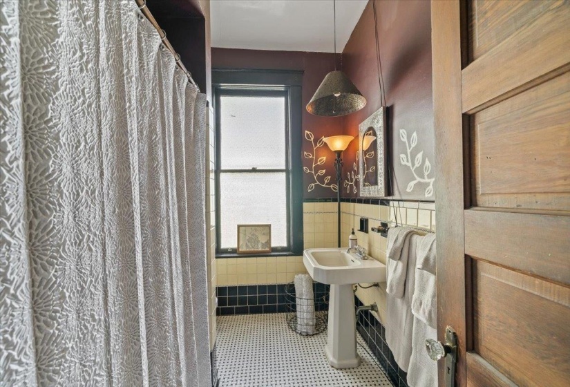 Bathroom with tile walls, curtained shower, light tile patterned floors, and a wainscoted wall