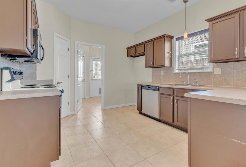 Kitchen with backsplash, light countertops, stainless steel appliances, and light tile patterned floors
