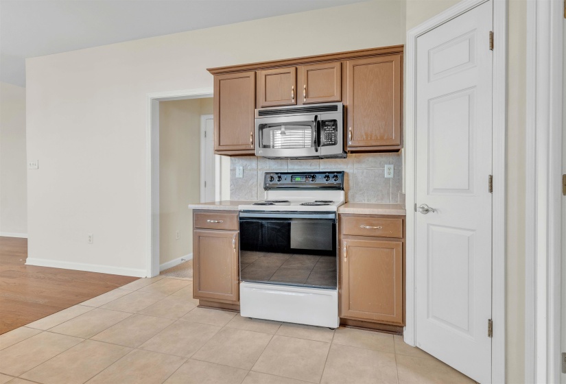 Kitchen with range with electric stovetop, light countertops, stainless steel microwave, and light tile patterned floors