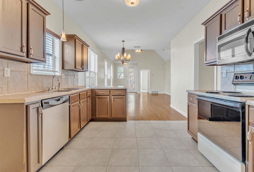 Kitchen with decorative backsplash, stainless steel appliances, light countertops, a peninsula, and hanging lights