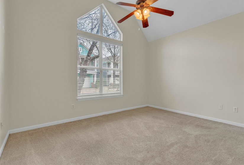 Empty room featuring a ceiling fan, light carpet, and lofted ceiling