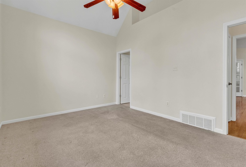 Carpeted spare room with vaulted ceiling and a ceiling fan
