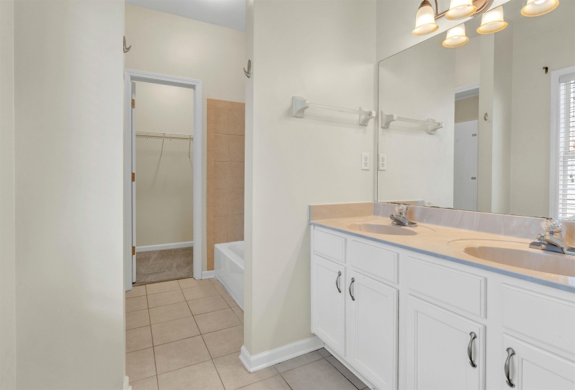 Full bath featuring double vanity, light tile patterned floors, and a spacious closet