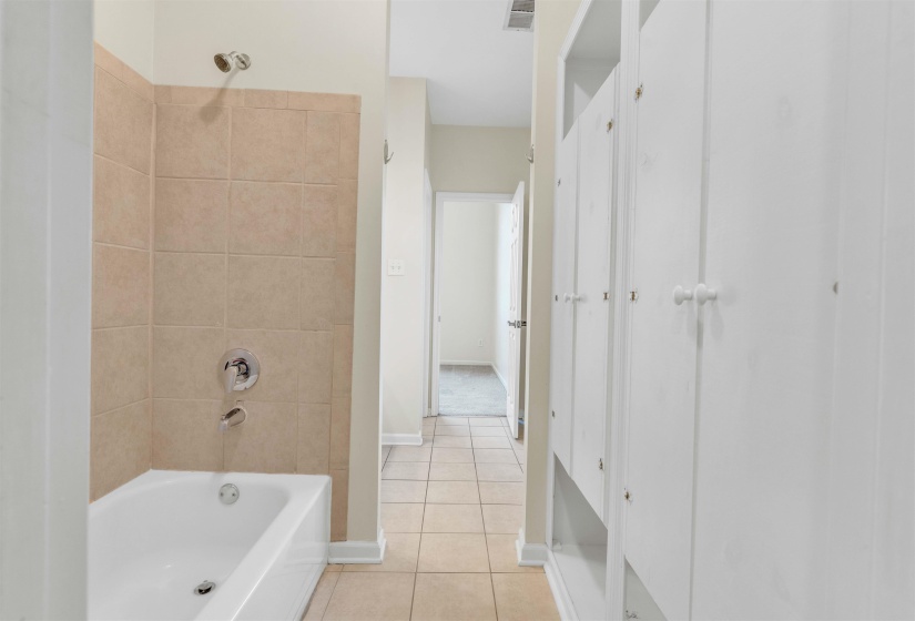 Bathroom with washtub / shower combination and light tile patterned flooring