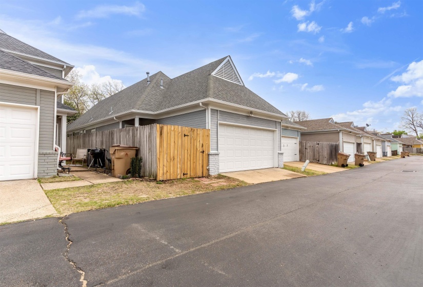 View of side of property featuring a gate, roof with shingles, a residential view, and brick siding
