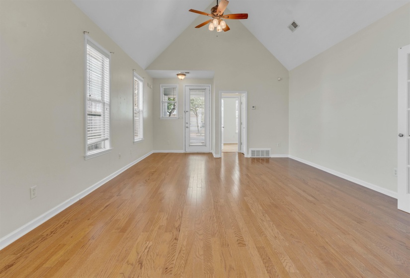 Unfurnished living room with a high ceiling, light wood-type flooring, and a ceiling fan
