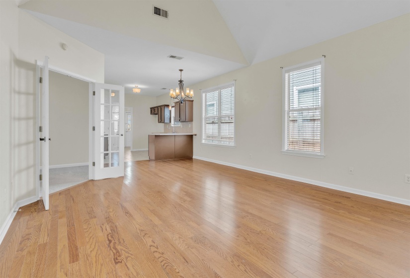 Unfurnished living room featuring hanging lights, light wood-style floors, and vaulted ceiling