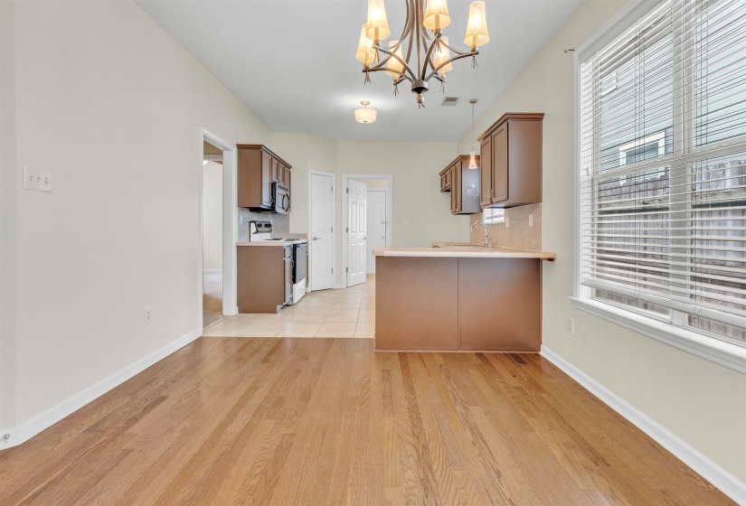 Kitchen featuring light countertops, suspended lighting, light wood-style floors, electric range, and wood finish cabinets