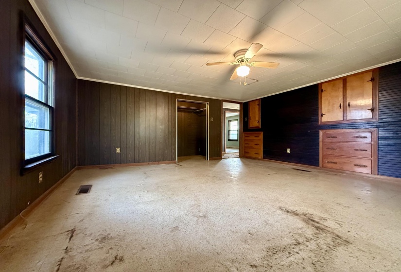 Unfurnished bedroom featuring wooden walls, a closet, and a ceiling fan