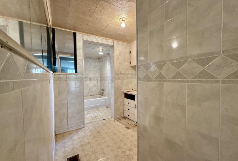 Bathroom with tile walls, vanity, light floors, and  shower combination