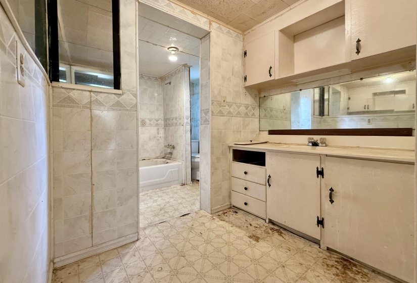Bathroom featuring tile walls, vanity, light floors, and shower / tub combination