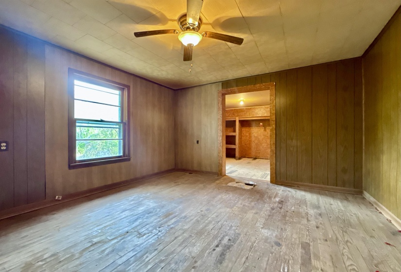 Empty room with wooden walls, hardwood / wood-style floors, and a ceiling fan