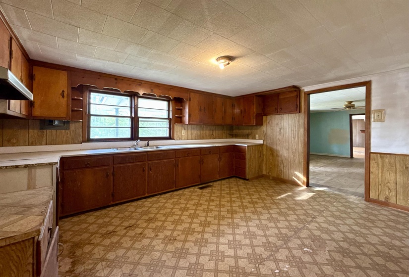 Kitchen featuring wooden walls, light countertops, light floors, wood finish cabinetry, and open shelves