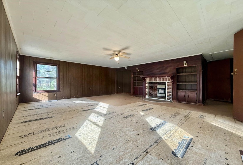 Unfurnished living room featuring wood walls, a fireplace, and ceiling fan
