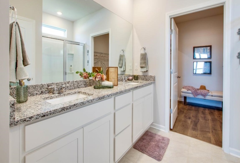 Full bath with double vanity, a stall shower, light tile patterned floors, and a walk in closet