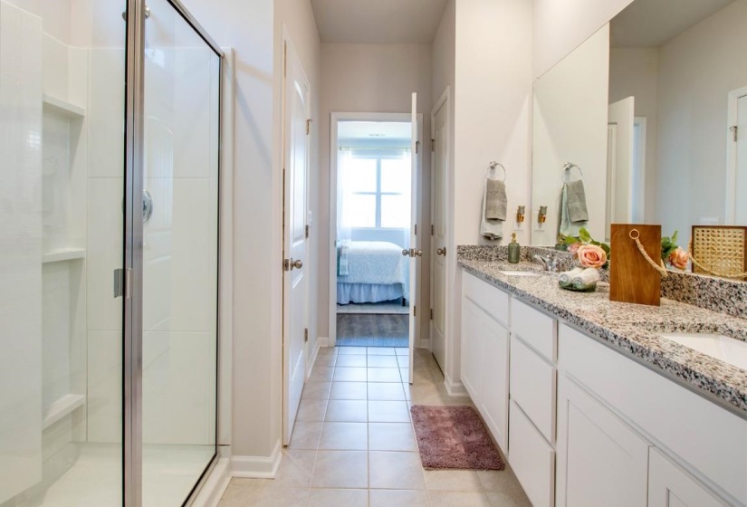 Full bath with connected bathroom, a stall shower, double vanity, and light tile patterned flooring