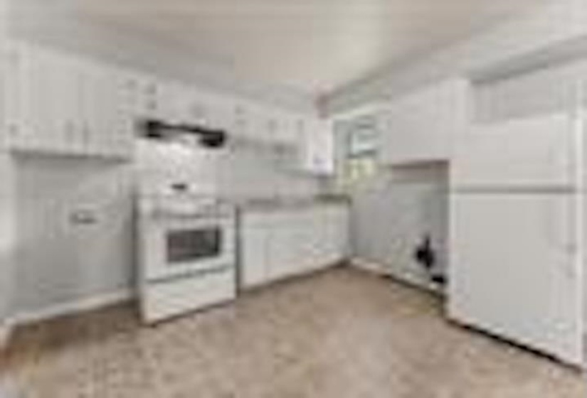 Kitchen with white cabinets, light countertops, and white range