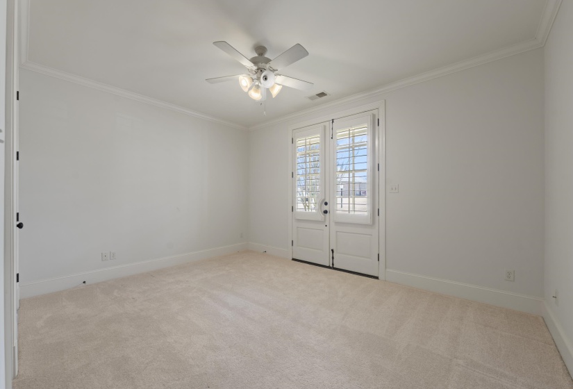 Empty room featuring light carpet, a ceiling fan, and crown molding