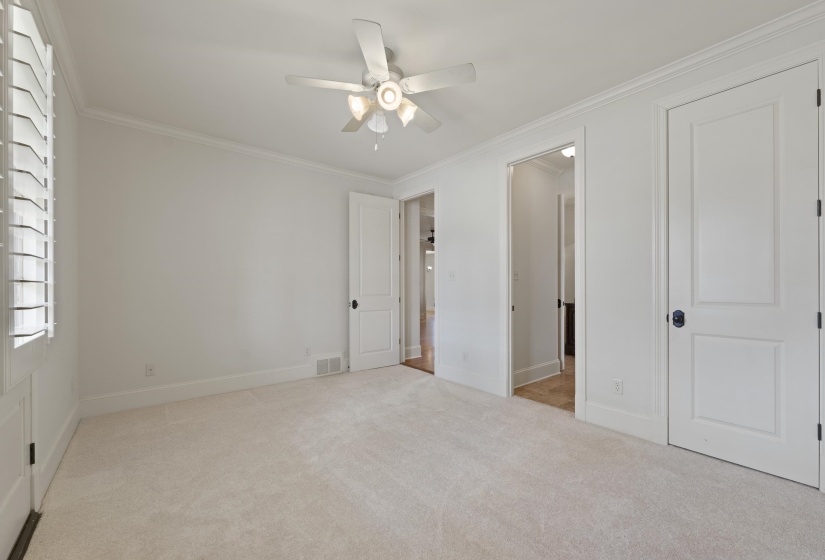 Unfurnished bedroom with light colored carpet, ornamental molding, and ceiling fan