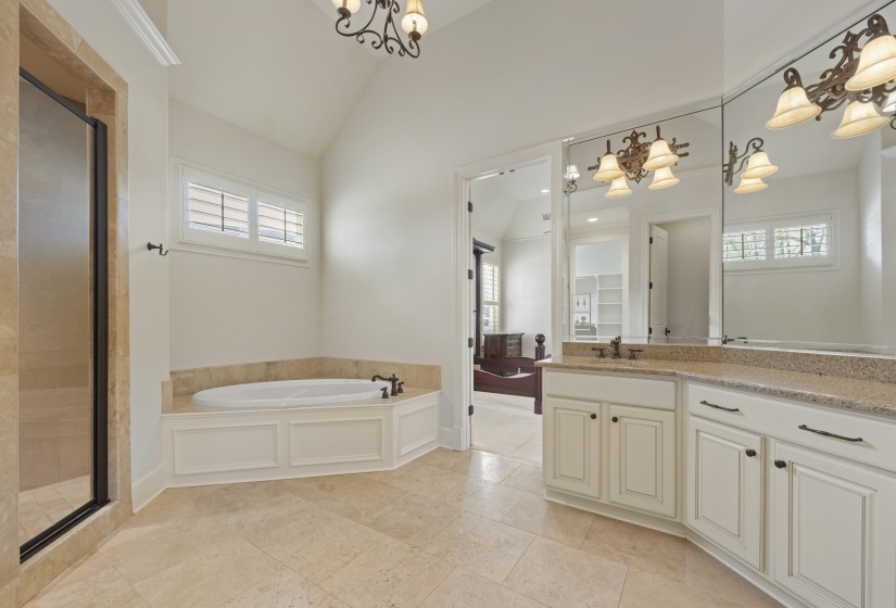 Ensuite bathroom featuring suspended lighting, a bath, vanity, vaulted ceiling, and a shower stall