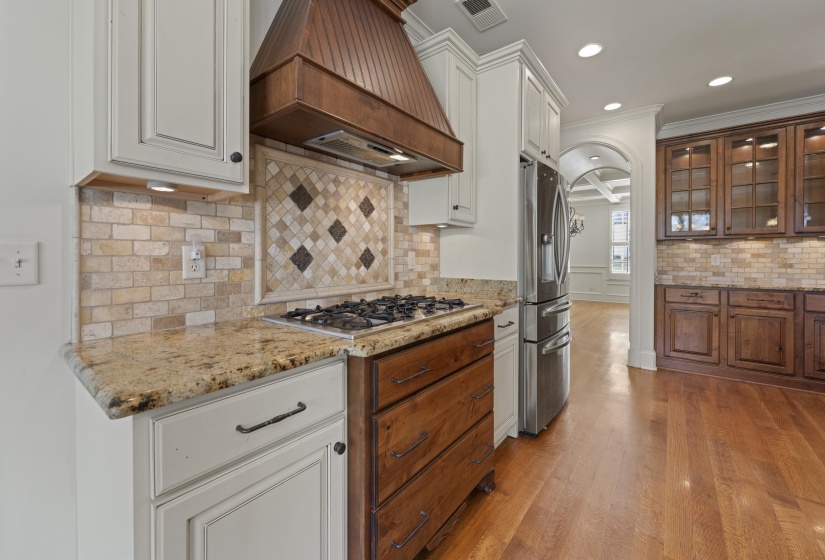Kitchen featuring glass fronted cabinets, light stone counters, light wood finished floors, stainless steel appliances, and recessed lighting