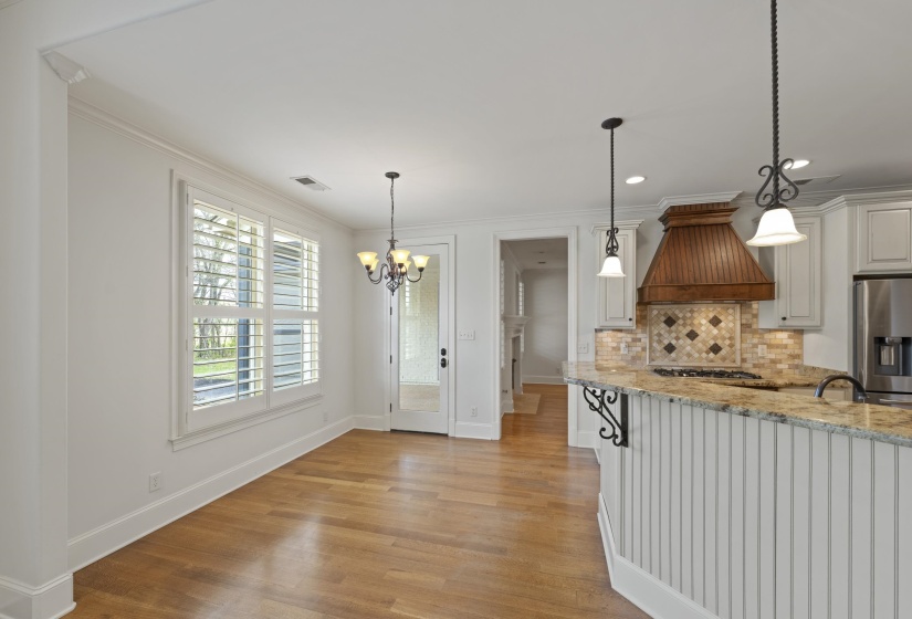 Kitchen featuring light stone counters, decorative backsplash, a chandelier, light wood-style flooring, and stainless steel fridge with ice dispenser