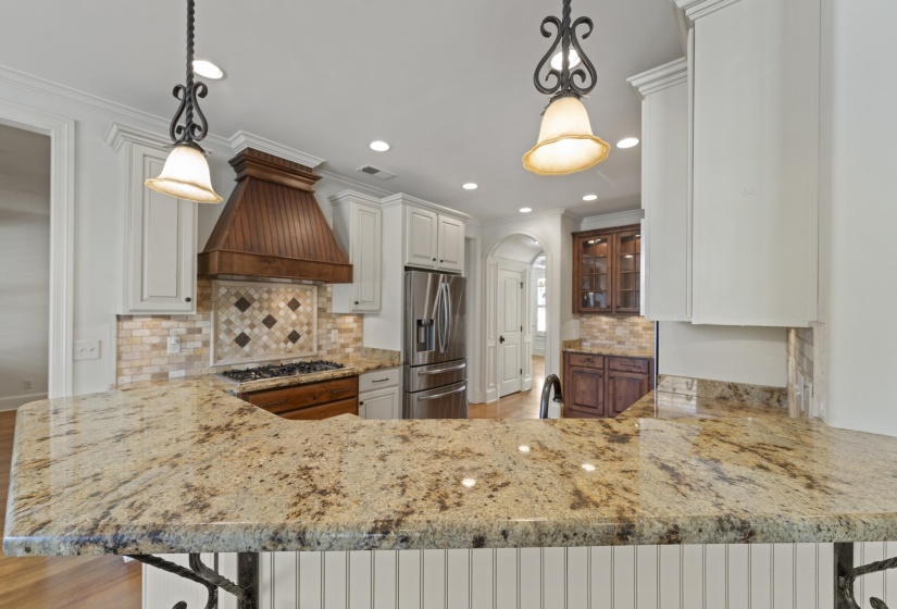 Kitchen featuring light stone countertops, a peninsula, a kitchen bar, stainless steel appliances, and ornamental molding
