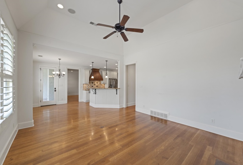 Unfurnished living room featuring light wood-style floors, ceiling fan, and a chandelier