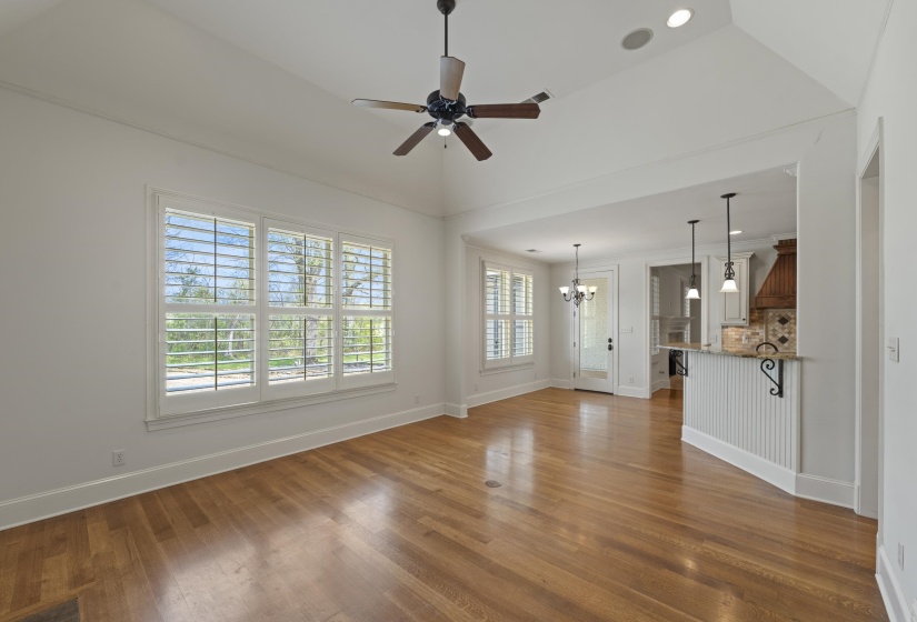 Unfurnished living room with ceiling fan, suspended lighting, dark wood-type flooring, healthy amount of natural light, and lofted ceiling