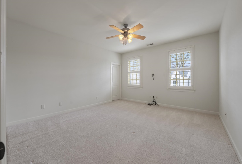 Empty room with light colored carpet and ceiling fan