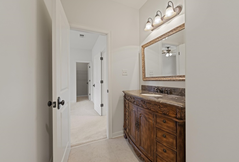Bathroom featuring vanity, ceiling fan, light colored carpet, and light tile patterned flooring