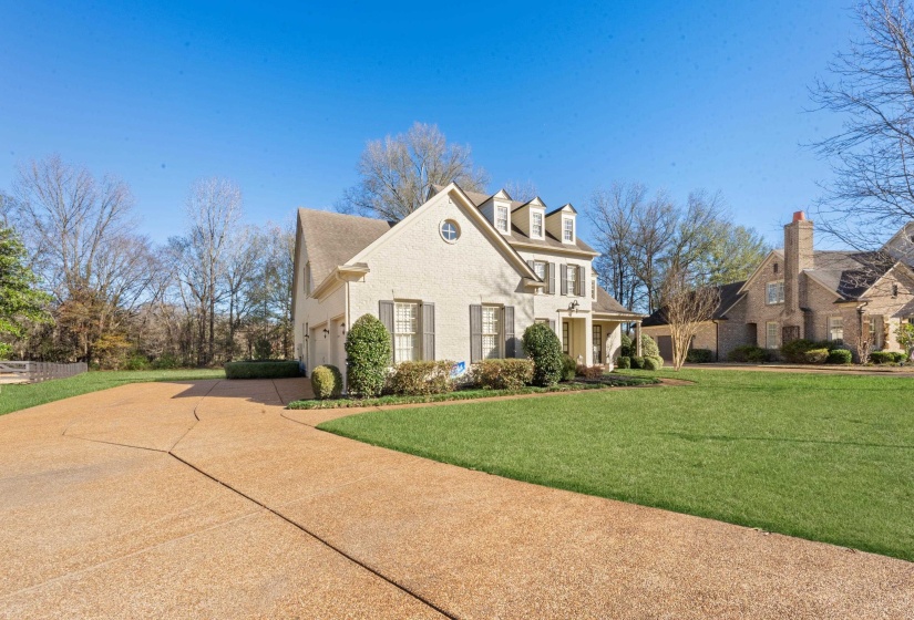 View of front of property featuring a front lawn, concrete driveway, and brick siding