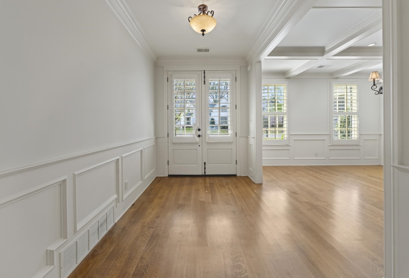 Entrance foyer with coffered ceiling, wood-type flooring, ornamental molding, a decorative wall, and french doors