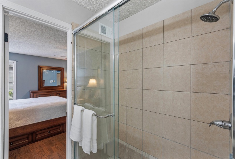 Ensuite bathroom featuring a textured ceiling, a stall shower, and wood finished floors