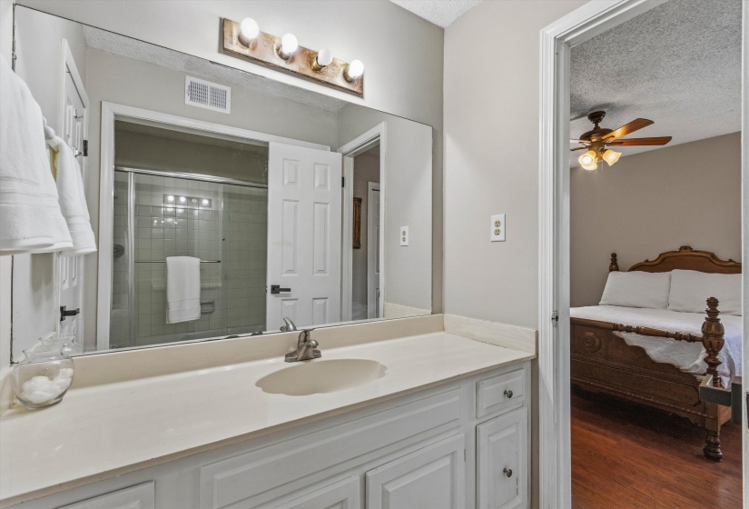 Ensuite bathroom featuring a textured ceiling, vanity, ceiling fan, a shower stall, and dark wood-style flooring