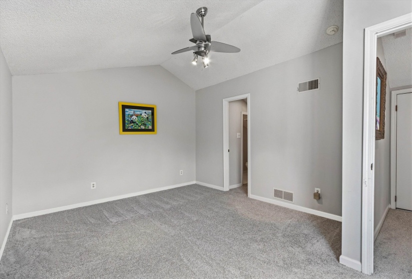 Unfurnished bedroom featuring light colored carpet, a ceiling fan, and a textured ceiling