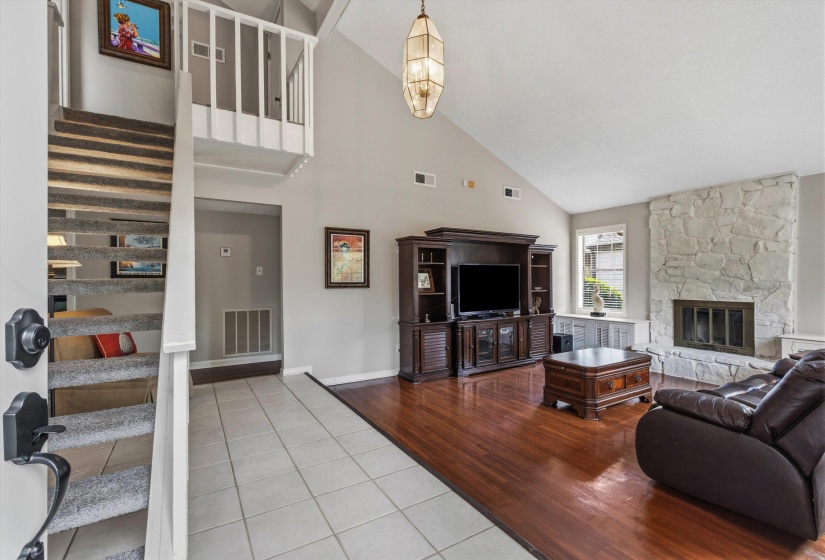 Living room featuring light tile patterned floors, vaulted ceiling, and a fireplace