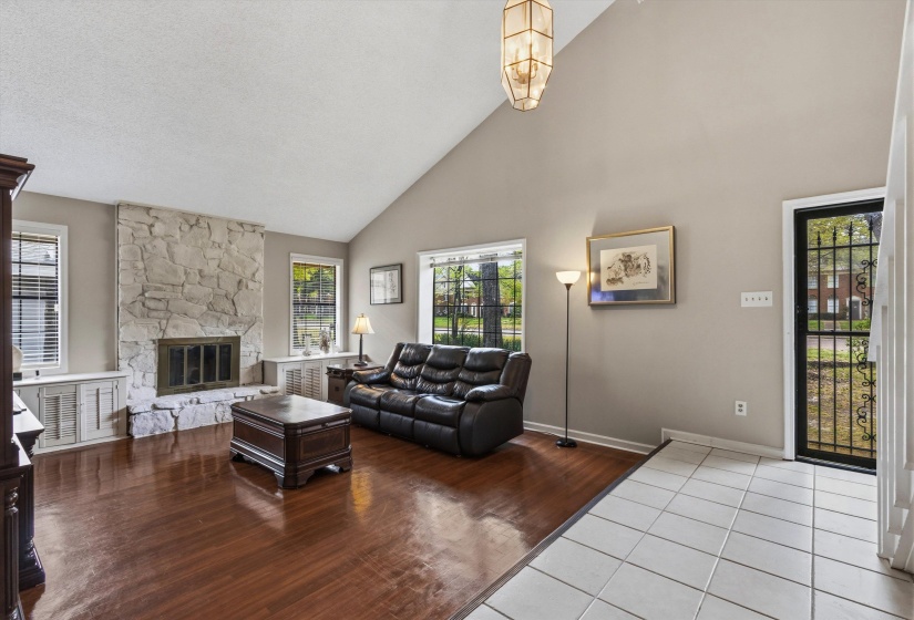 Living area featuring vaulted ceiling, wood finished floors, a fireplace, and hanging lights