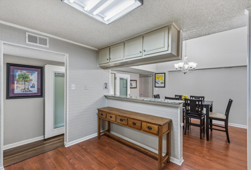 Kitchen featuring light stone countertops, a chandelier, a peninsula, a textured ceiling, and dark wood-type flooring