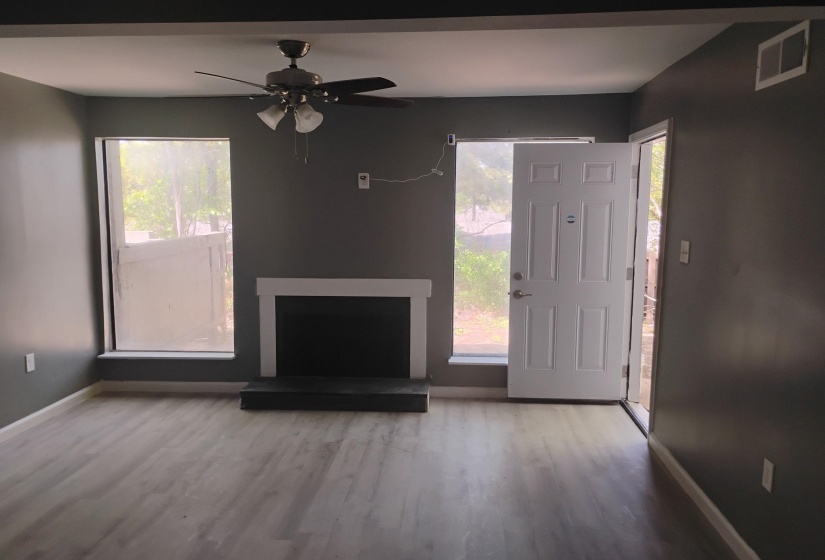 Unfurnished living room with wood finished floors, ceiling fan, and healthy amount of natural light