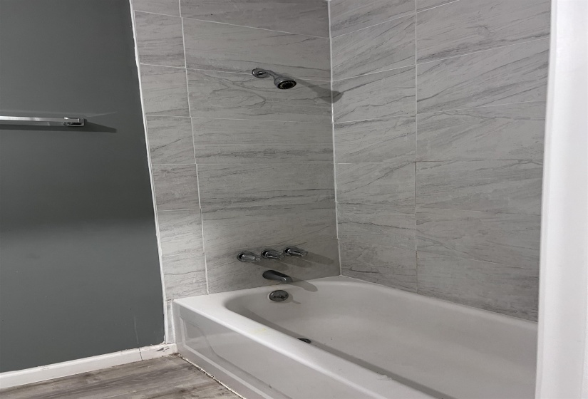 Bathroom featuring washtub / shower combination and light wood-type flooring
