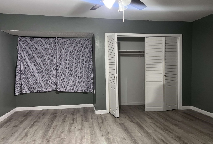 Unfurnished bedroom featuring wood finished floors, a closet, and ceiling fan