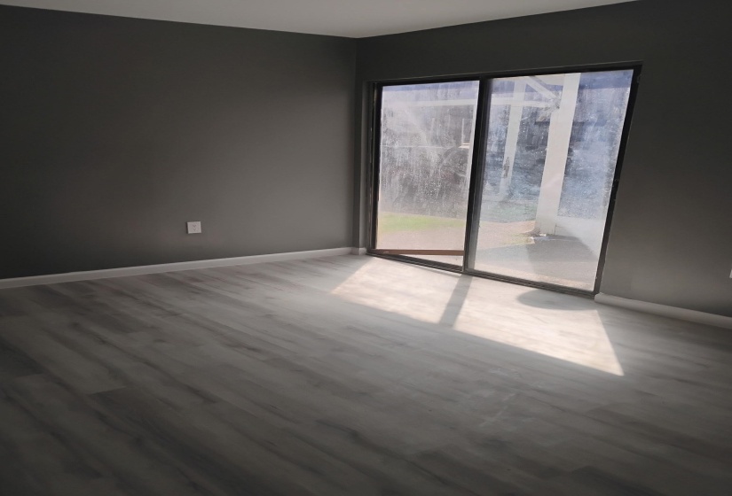 Unfurnished room featuring wood finished floors and baseboards and Sliding Glass Door.